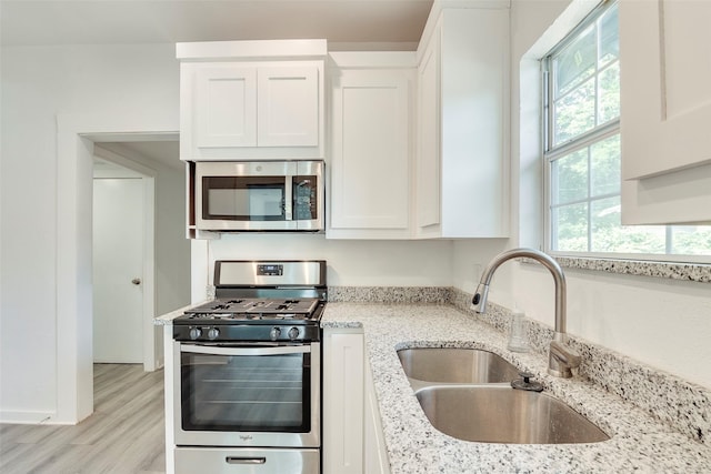 4423 Colonial Ave, Dallas, TX 75215 - kitchen with stainless steel appliances, a sink, light stone counters, white cabinetry, and light wood-style flooring