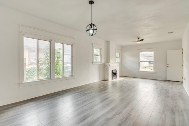 4423 Colonial Ave, Dallas, TX 75215 - unfurnished living room featuring healthy amount of natural light, wood finished floors, a ceiling fan, and a fireplace