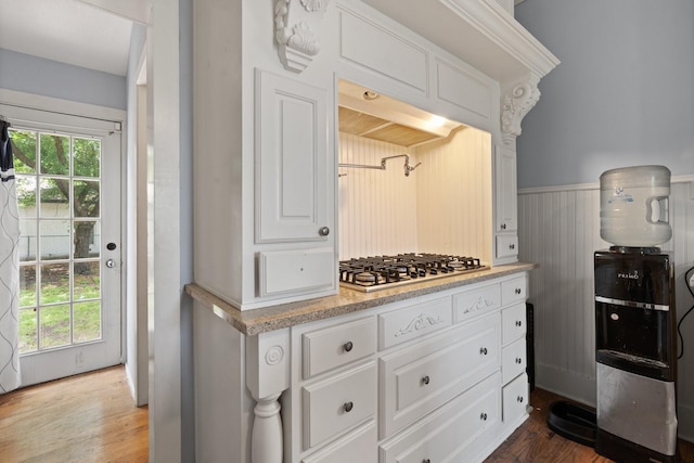 229 College, Italy, TX 76651 - kitchen featuring light countertops, wood finished floors, white cabinetry, stainless steel gas stovetop, and wainscoting