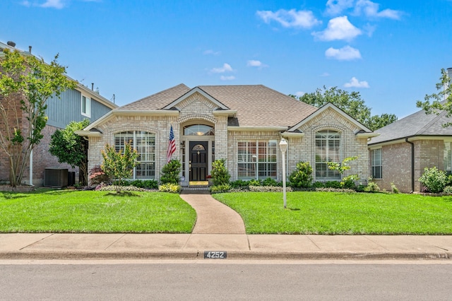 4252 Millview Ln, Dallas, TX 75287 - french provincial home with brick siding, a front lawn, central AC unit, and a shingled roof