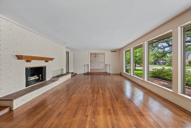 2900 Simondale Dr, Fort Worth, TX 76109 - unfurnished living room featuring wood finished floors, a brick fireplace, and baseboards