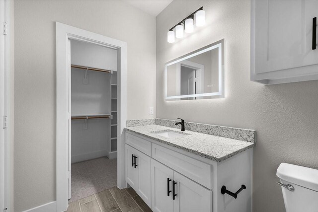 4405 Baylor St, Fort Worth, TX 76119 - bathroom with vanity, toilet, wood finished floors, and a walk in closet
