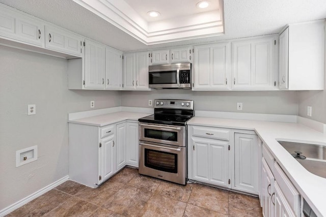 229 S Heartz Rd, Coppell, TX 75019 - kitchen with stainless steel appliances, white cabinets, light countertops, recessed lighting, and a raised ceiling