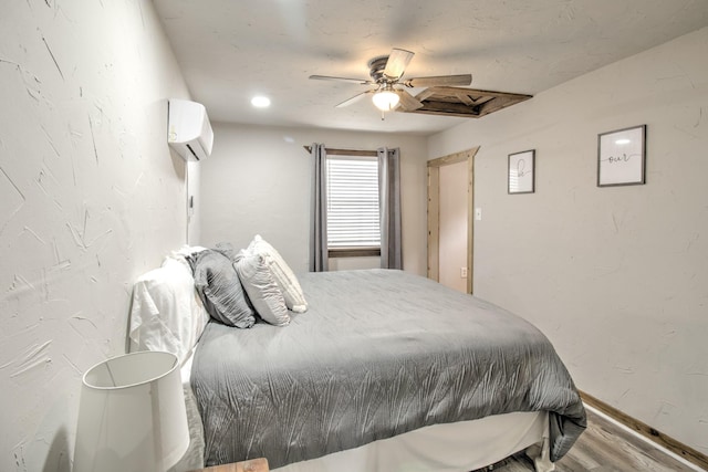 179 Oak St, Nocona, TX 76255 - bedroom with a wall unit AC, wood finished floors, baseboards, and ceiling fan