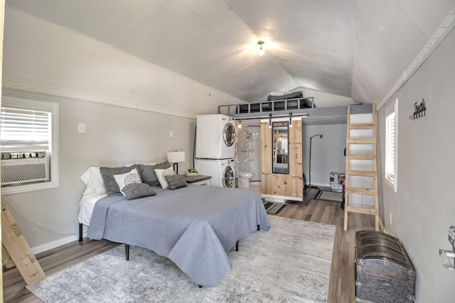 179 Oak St, Nocona, TX 76255 - bedroom featuring estacked washer and dryer, wood finished floors, vaulted ceiling, cooling unit, and baseboards