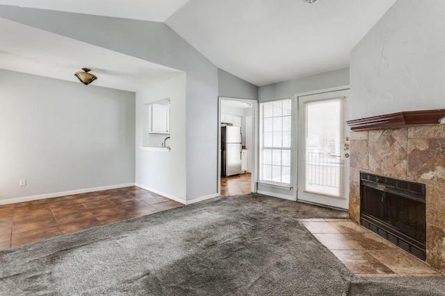 9601 Forest Ln Unit 822, Dallas, TX 75243 - unfurnished living room featuring lofted ceiling, a fireplace, carpet flooring, baseboards, and tile patterned floors