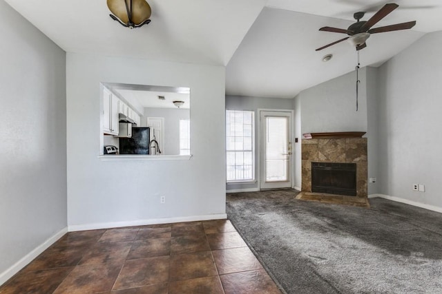 9601 Forest Ln Unit 822, Dallas, TX 75243 - unfurnished living room with ceiling fan, a tiled fireplace, baseboards, and lofted ceiling