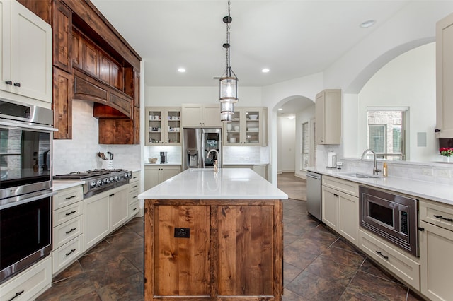 968 Fairfield Ln, Allen, TX 75013 - kitchen with a sink, stainless steel appliances, arched walkways, decorative backsplash, and light countertops