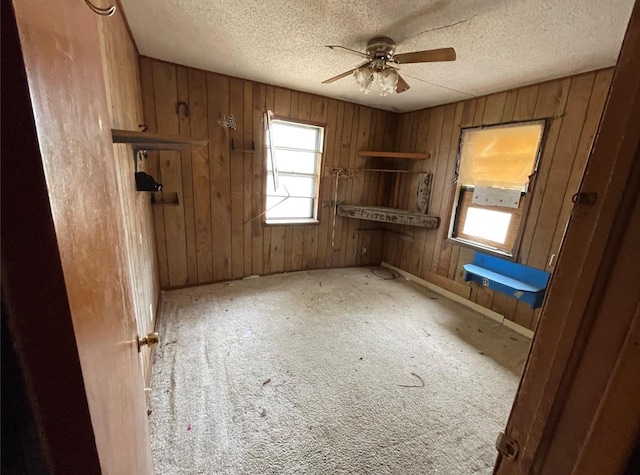 307 N 4th St, Crandall, TX 75114 - spare room with a ceiling fan, wood walls, baseboards, a textured ceiling, and carpet floors