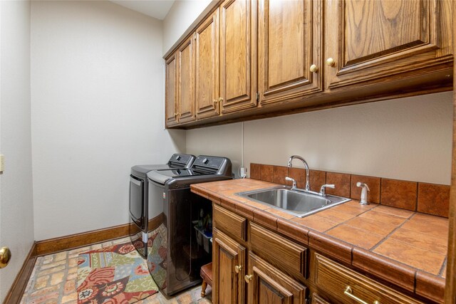 clothes washing area with separate washer and dryer, cabinet space, and baseboards