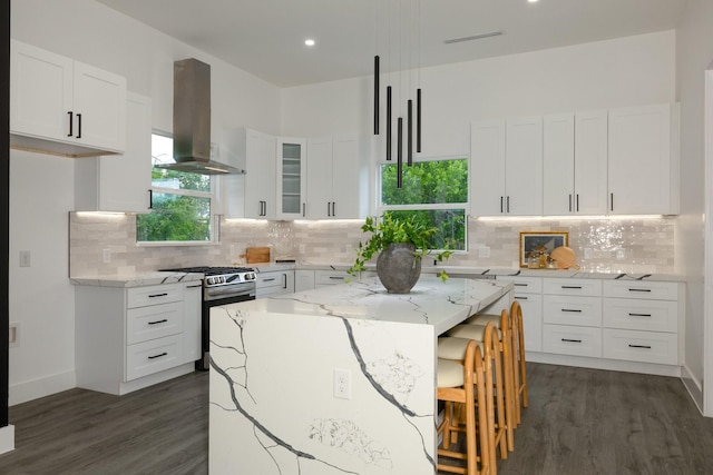 1921 Pollard St, Dallas, TX 75208 - kitchen featuring island exhaust hood, gas stove, dark wood-style floors, light stone countertops, and a kitchen breakfast bar