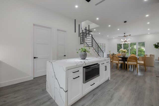 1921 Pollard St, Dallas, TX 75208 - kitchen with stainless steel microwave, white cabinetry, a kitchen island, light wood-type flooring, and recessed lighting