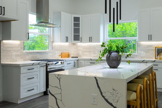 1921 Pollard St, Dallas, TX 75208 - kitchen featuring island exhaust hood, stainless steel range with gas stovetop, a kitchen bar, and white cabinetry