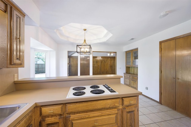 kitchen with white electric stovetop, brown cabinetry, and light countertops
