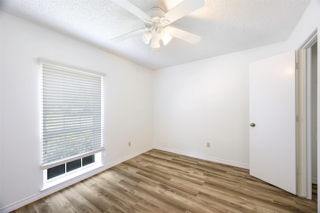 spare room with wood finished floors, ceiling fan, a textured ceiling, and baseboards