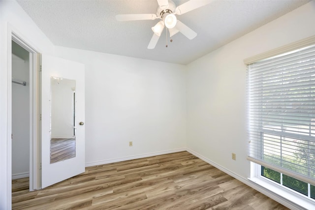spare room featuring light wood-style flooring, baseboards, and ceiling fan