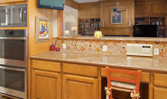 1706 Kiowa, Graham, TX 76450 - kitchen with stainless steel double oven, backsplash, light stone countertops, and a ceiling fan