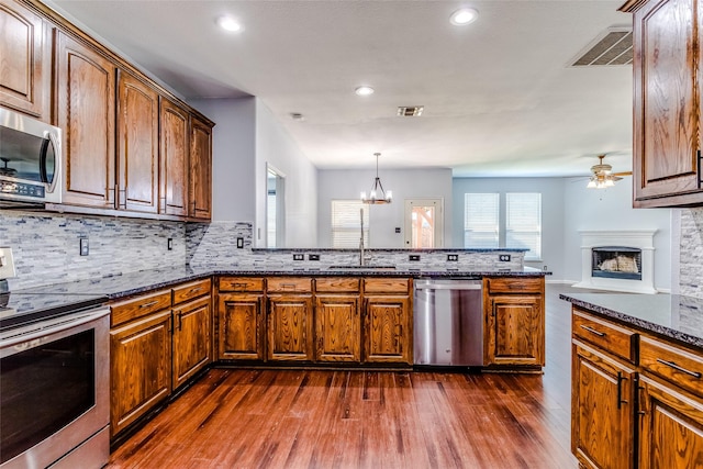 2007 Brazoria Dr, Forney, TX 75126 - kitchen featuring appliances with stainless steel finishes, ceiling fan, a peninsula, dark wood-type flooring, and backsplash