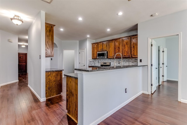 2007 Brazoria Dr, Forney, TX 75126 - kitchen with appliances with stainless steel finishes, dark wood-style floors, tasteful backsplash, dark stone countertops, and arched walkways