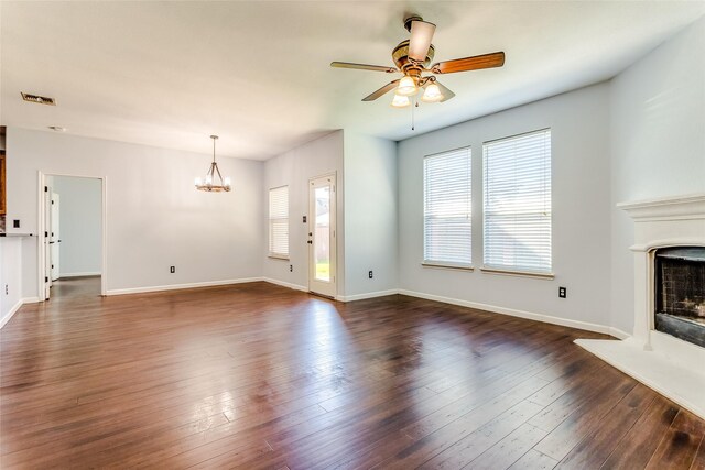 2007 Brazoria Dr, Forney, TX 75126 - unfurnished living room featuring a fireplace with raised hearth, a ceiling fan, a chandelier, and dark wood-style floors