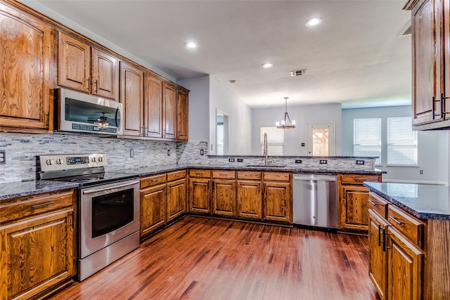 2007 Brazoria Dr, Forney, TX 75126 - kitchen featuring appliances with stainless steel finishes, a sink, a peninsula, dark wood-style floors, and brown cabinets