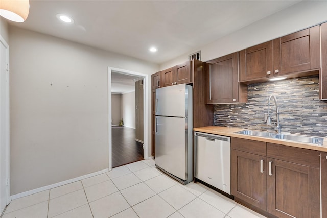 kitchen featuring freestanding refrigerator, dishwasher, a sink, decorative backsplash, and light countertops