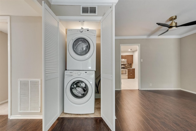 laundry room with stacked washer / drying machine, ceiling fan, wood finished floors, ornamental molding, and baseboards