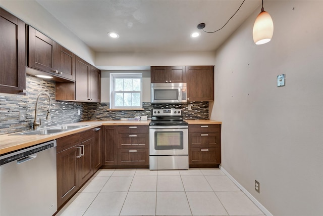 kitchen featuring stainless steel appliances, a sink, tasteful backsplash, dark brown cabinetry, and light tile patterned floors