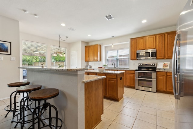 1016 Hidden Creek Ct, Allen, TX 75002 - kitchen featuring stainless steel appliances, a kitchen island, light tile patterned floors, brown cabinets, and recessed lighting