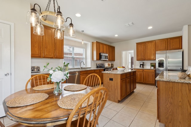 1016 Hidden Creek Ct, Allen, TX 75002 - kitchen featuring stainless steel appliances, a sink, a center island, brown cabinetry, and light tile patterned floors
