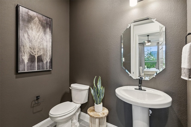 half bath with toilet, baseboards, and ceiling fan