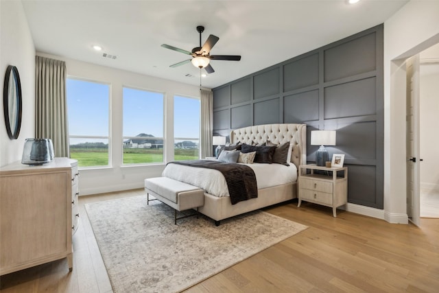 bedroom with a decorative wall, light wood finished floors, recessed lighting, baseboards, and a ceiling fan