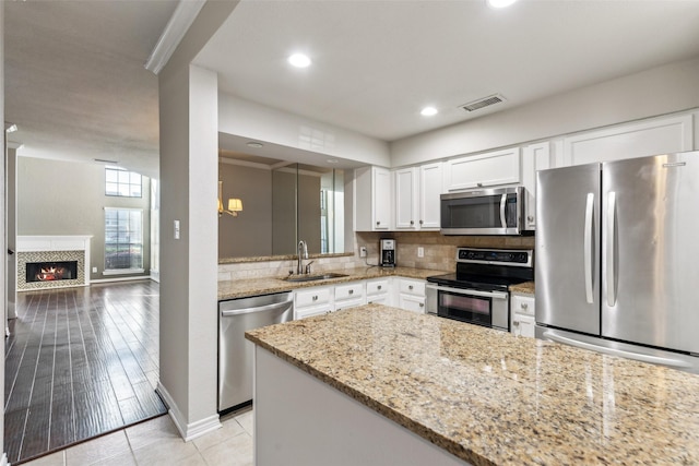 14333 Preston Rd Unit 1103, Dallas, TX 75254 - kitchen featuring stainless steel appliances, a sink, backsplash, white cabinets, and light stone counters