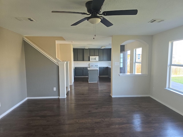 8313 French Quarter Ln, Fort Worth, TX 76123 - unfurnished living room featuring dark wood-style flooring, ceiling fan, baseboards, a textured ceiling, and arched walkways