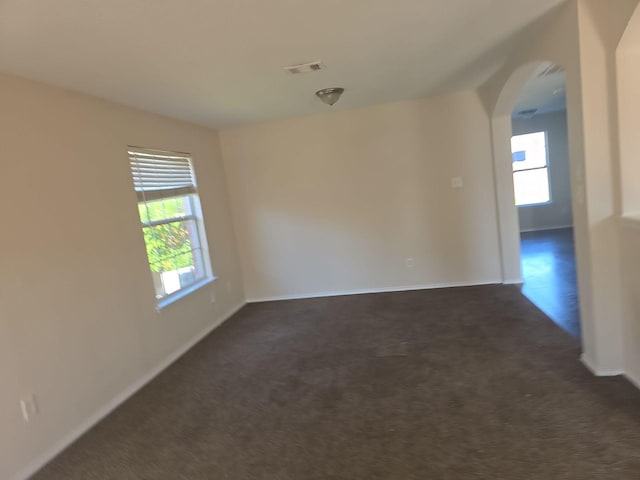 8313 French Quarter Ln, Fort Worth, TX 76123 - spare room featuring arched walkways, healthy amount of natural light, and dark colored carpet