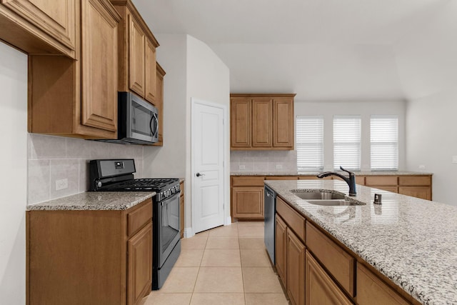 1105 Pigeon Hawk Dr, Little Elm, TX 75068 - kitchen featuring appliances with stainless steel finishes, a sink, tasteful backsplash, light stone counters, and brown cabinetry