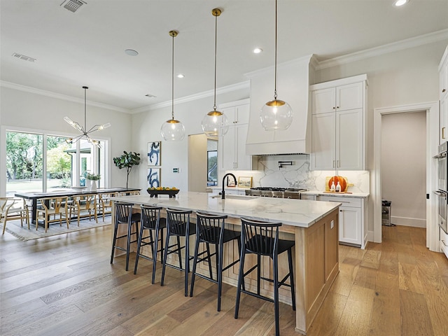 2015 Honey Ln, Celina, TX 75009 - kitchen featuring a spacious island, light stone counters, tasteful backsplash, light wood-style flooring, and white cabinets