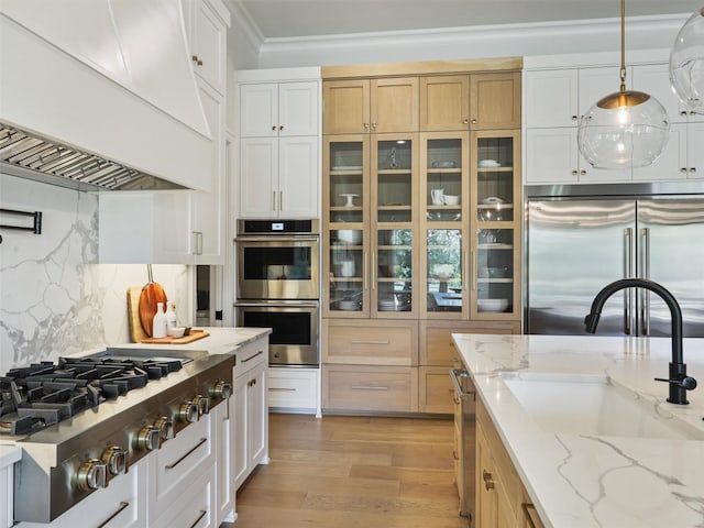 2015 Honey Ln, Celina, TX 75009 - kitchen with stainless steel appliances, premium range hood, glass insert cabinets, a sink, and light wood finished floors