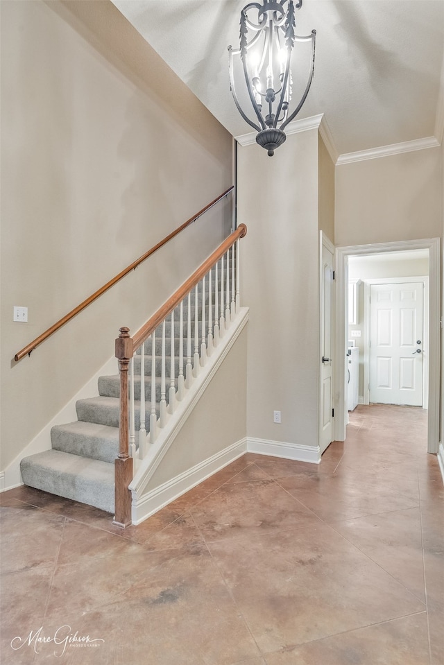 stairway featuring a chandelier, crown molding, baseboards, concrete flooring, and washer / dryer