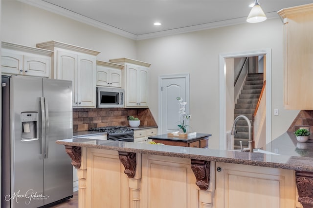 kitchen with appliances with stainless steel finishes, a sink, tasteful backsplash, dark stone countertops, and ornamental molding