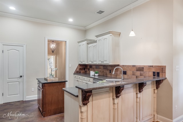 kitchen featuring a sink, decorative backsplash, ornamental molding, a peninsula, and a kitchen breakfast bar