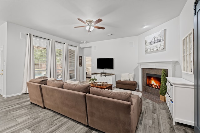 1701 Travis Ct, Allen, TX 75002 - living room with light wood-type flooring, a tiled fireplace, ceiling fan, and baseboards