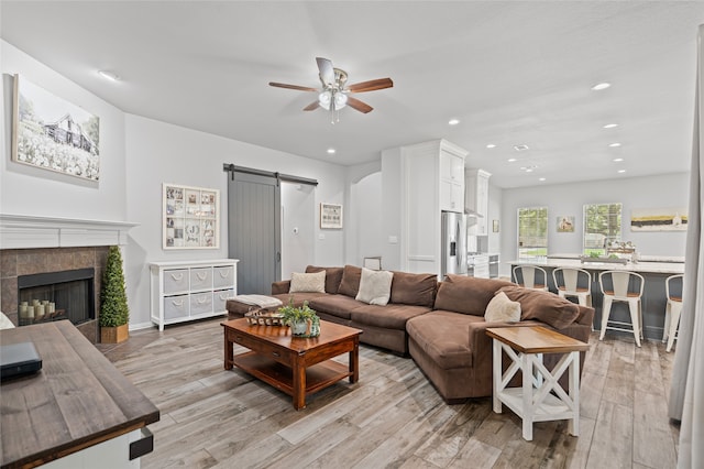 1701 Travis Ct, Allen, TX 75002 - living area featuring a barn door, ceiling fan, recessed lighting, light wood-style flooring, and a tiled fireplace