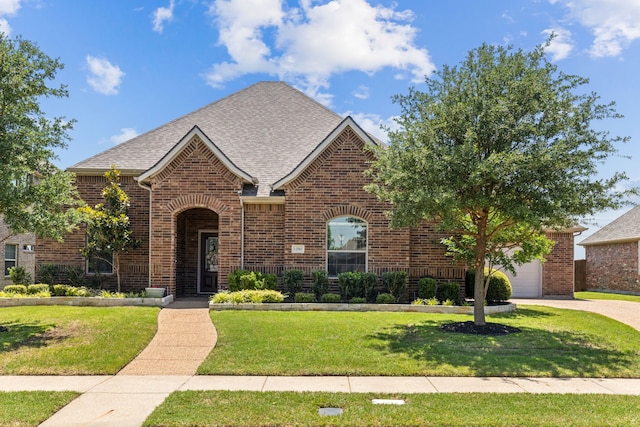 view of front of house featuring brick siding, a front lawn, roof with shingles, and driveway