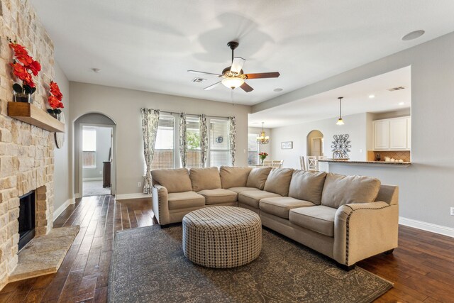 1250 Amistad Dr, Prosper, TX 75078 - living area with arched walkways, a ceiling fan, dark wood-type flooring, and a stone fireplace