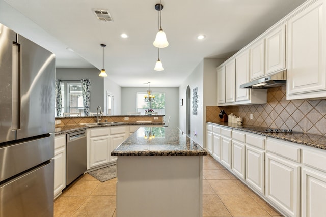 kitchen featuring stainless steel appliances, a sink, under cabinet range hood, tasteful backsplash, and recessed lighting