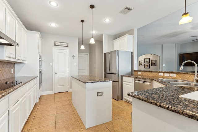 kitchen with appliances with stainless steel finishes, a sink, a kitchen island, decorative backsplash, and white cabinets