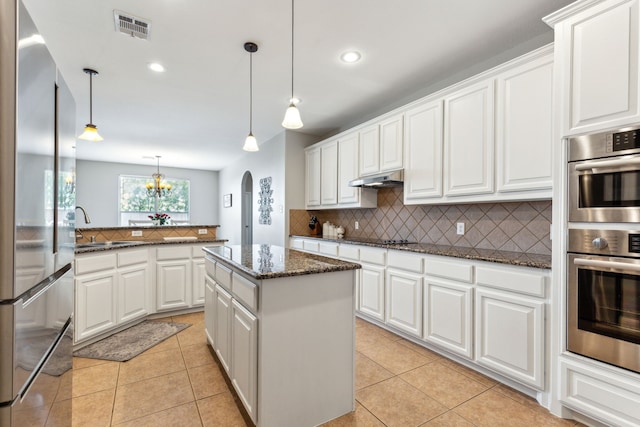 kitchen with appliances with stainless steel finishes, backsplash, a sink, arched walkways, and recessed lighting