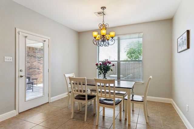 tiled dining space featuring a chandelier and baseboards