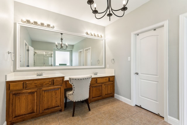 bathroom featuring a chandelier, double vanity, tile patterned floors, a shower with shower door, and baseboards